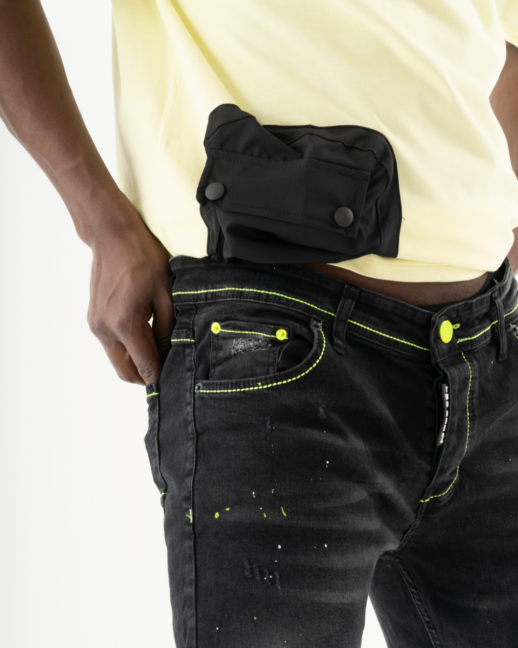 A man wearing ripped jeans is holding a black TWILIGHT in his pocket.