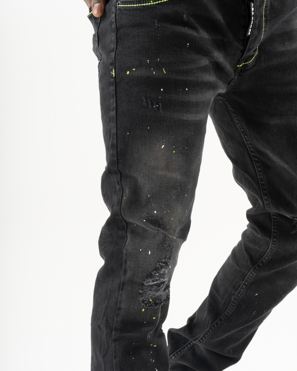 A man wearing a pair of black skinny TWILIGHT jeans with neon splatters.