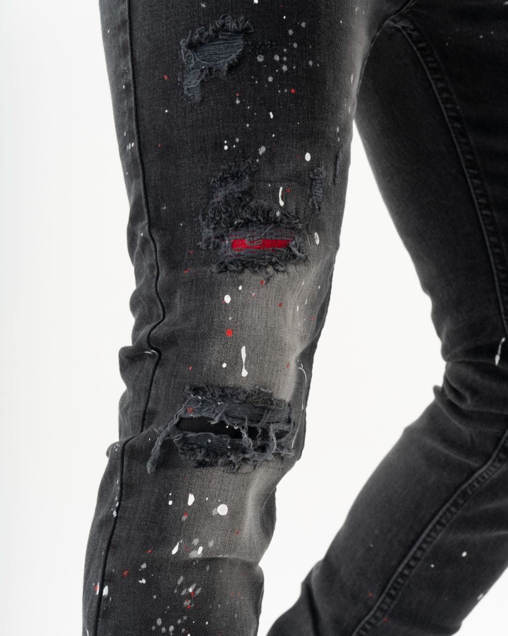 A pair of HOTSPOT skinny fit men's streetwear jeans with paint splatters on them.