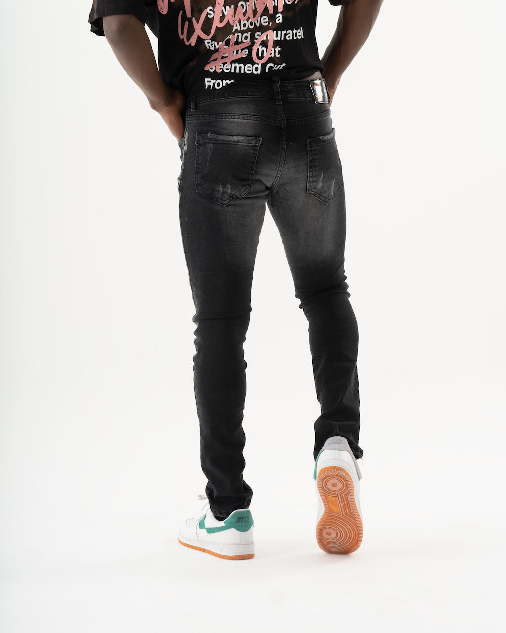 The back of a man wearing black ENRAGE made of elastic fabric, providing a smooth feel. The ENRAGE showcase a skinny fit and are paired with a t-shirt.