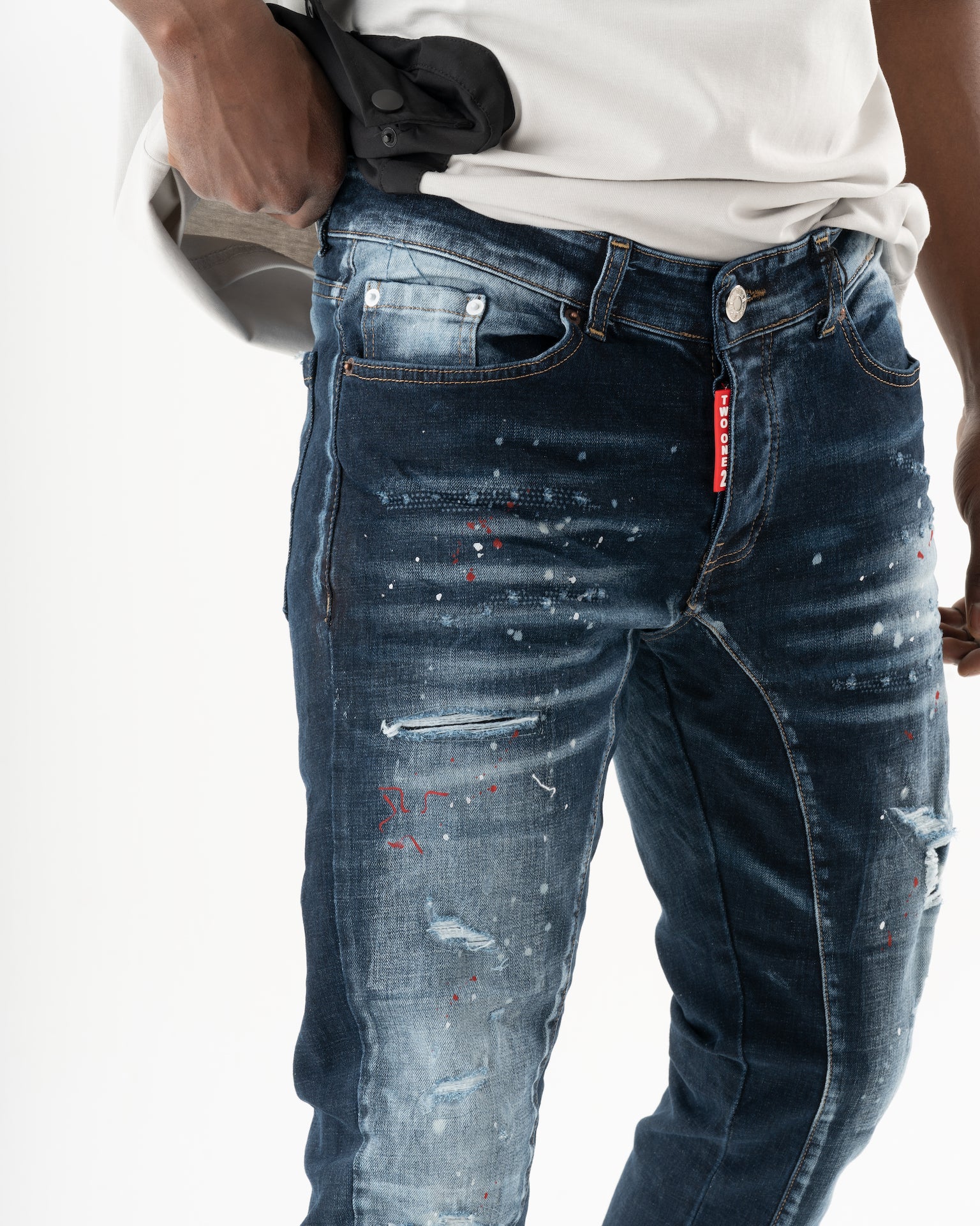 A man wearing a pair of STARLIGHT jeans with paint splatters on them.