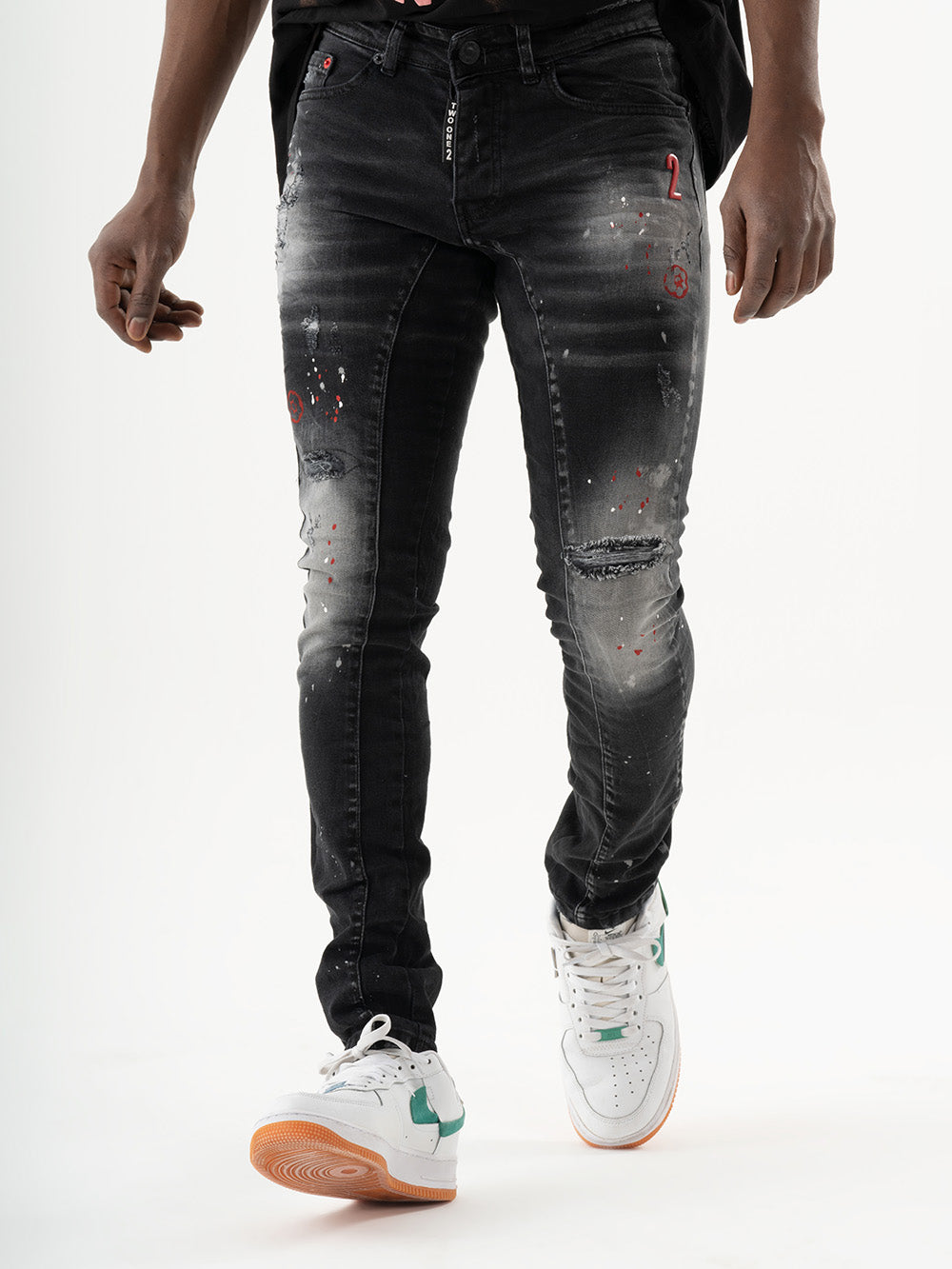 A man wearing ripped black THUNDERBIRD jeans with added stretch and sneakers.