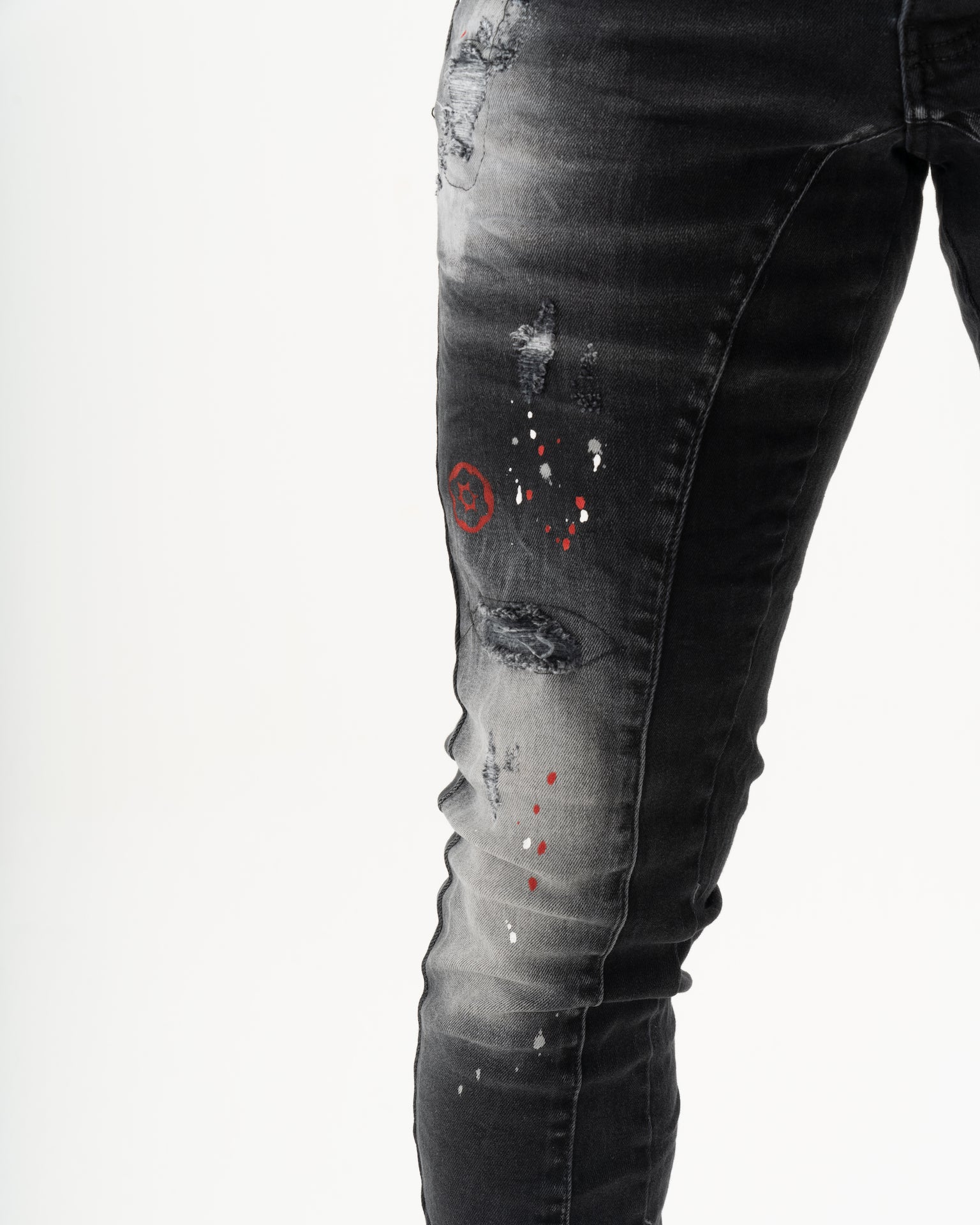 A man wearing a pair of THUNDERBIRD jeans with red paint splattered on them.