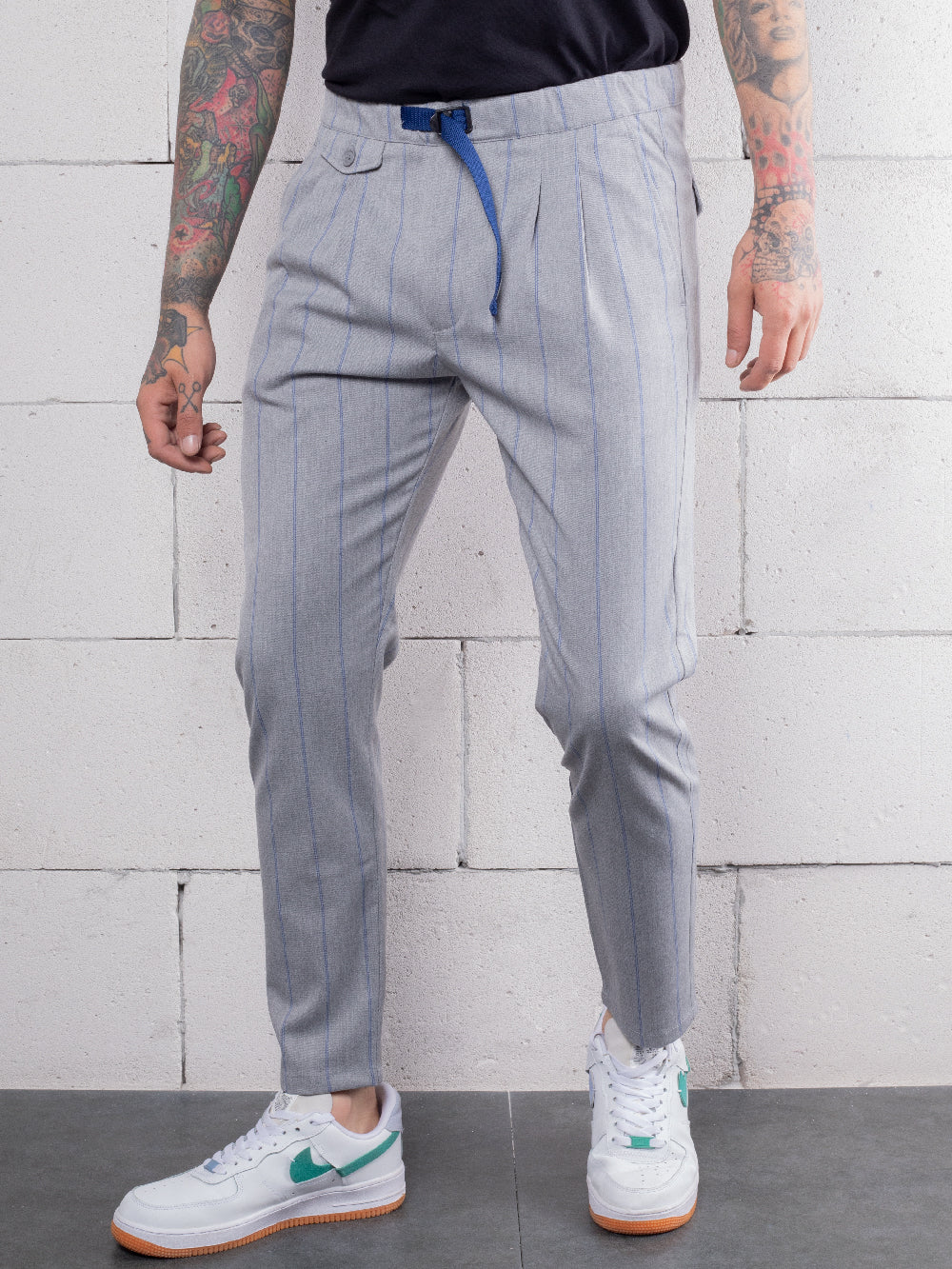 A man with hand crafted tattoos wearing RODEO DRIVE PANTS made from premium Italian fabric.