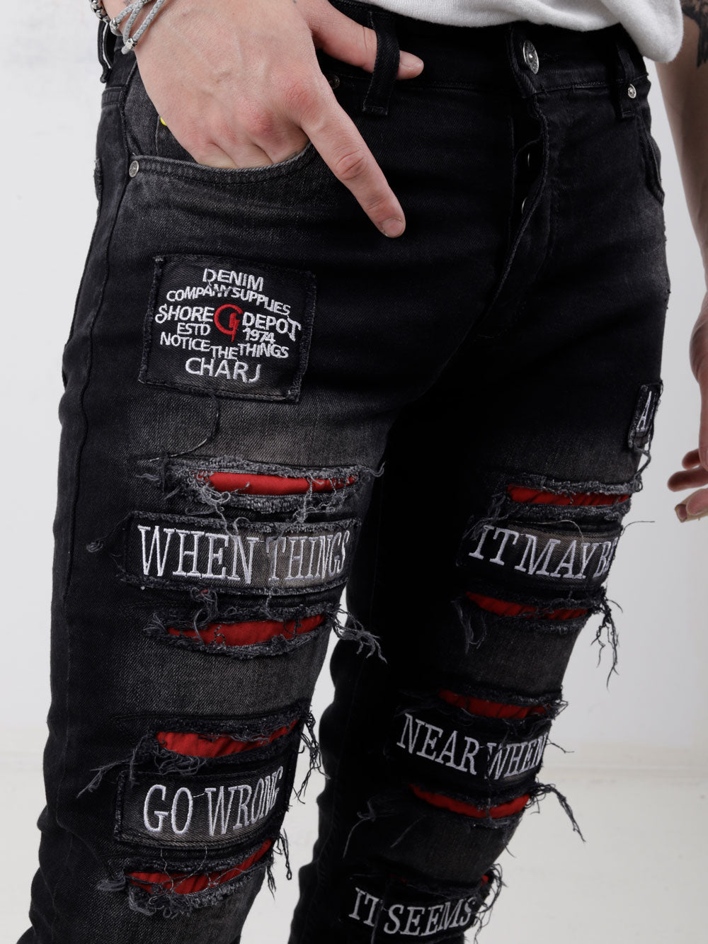 A man wearing a pair of PAW TRAIL jeans with red patches on them.