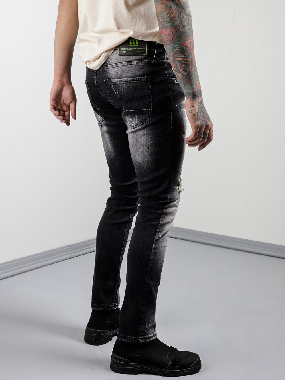 A man in NEON TALK jeans with tattoos standing in a room.