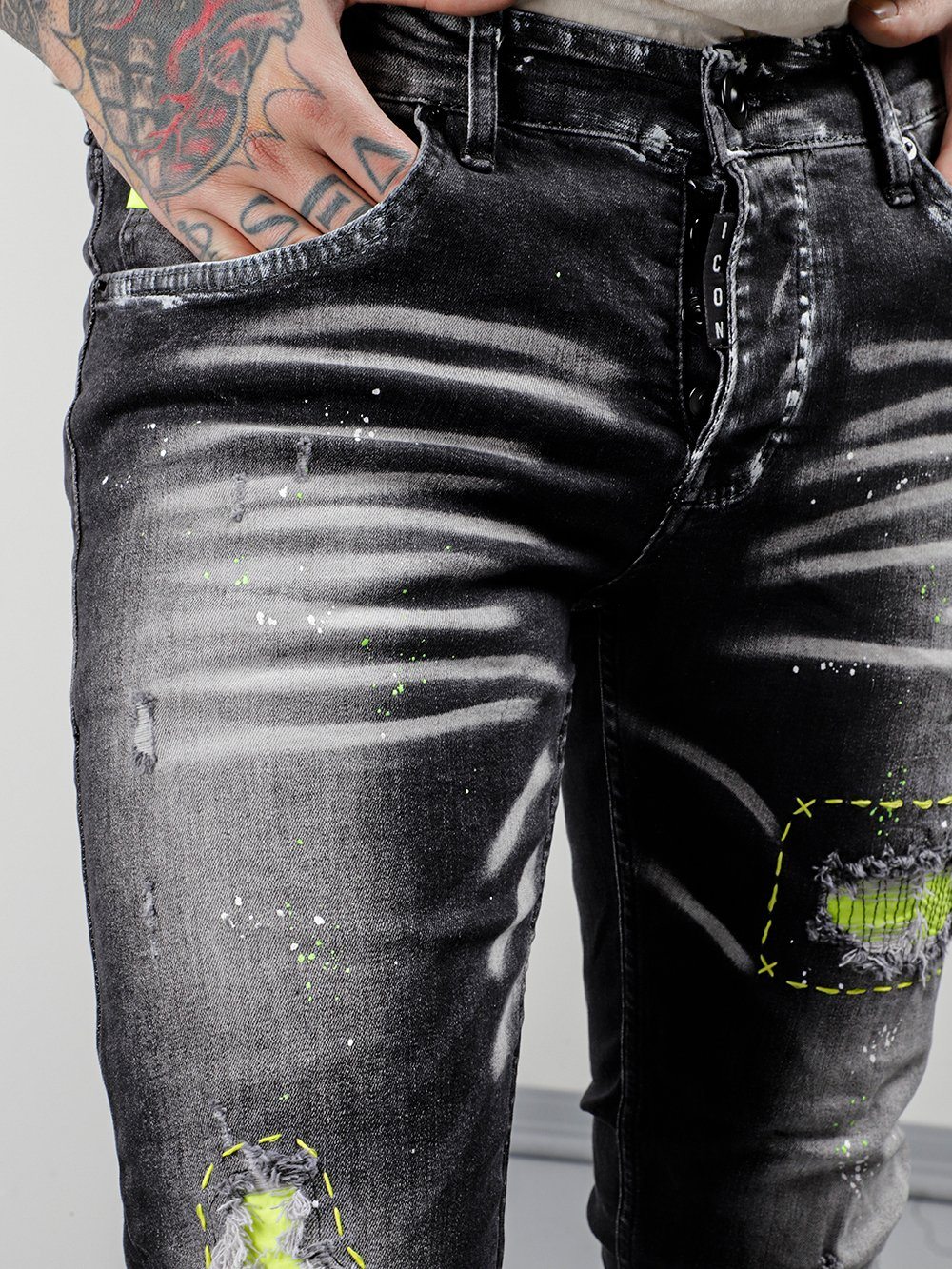 A man wearing a pair of black jeans with NEON TALK paint on them.