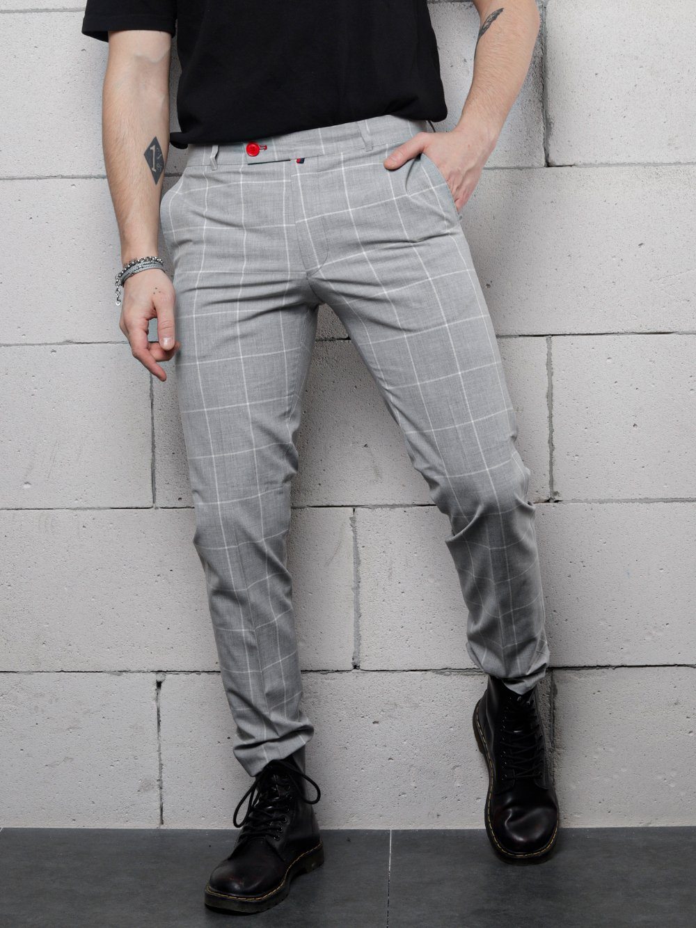 A man in a t-shirt and black pants is leaning against a wall wearing ICED AMERICANO PANTS.