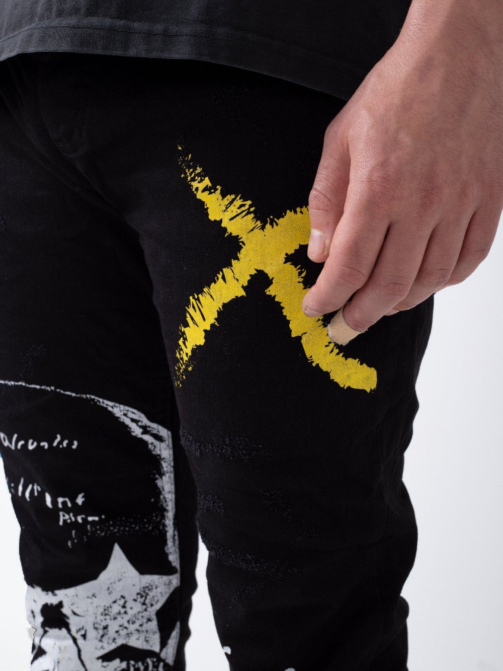 A man wearing a pair of black jeans with a yellow DEAN on them.