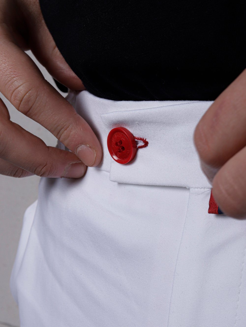 A man is putting a Cream Frappuccino button on his white pants.