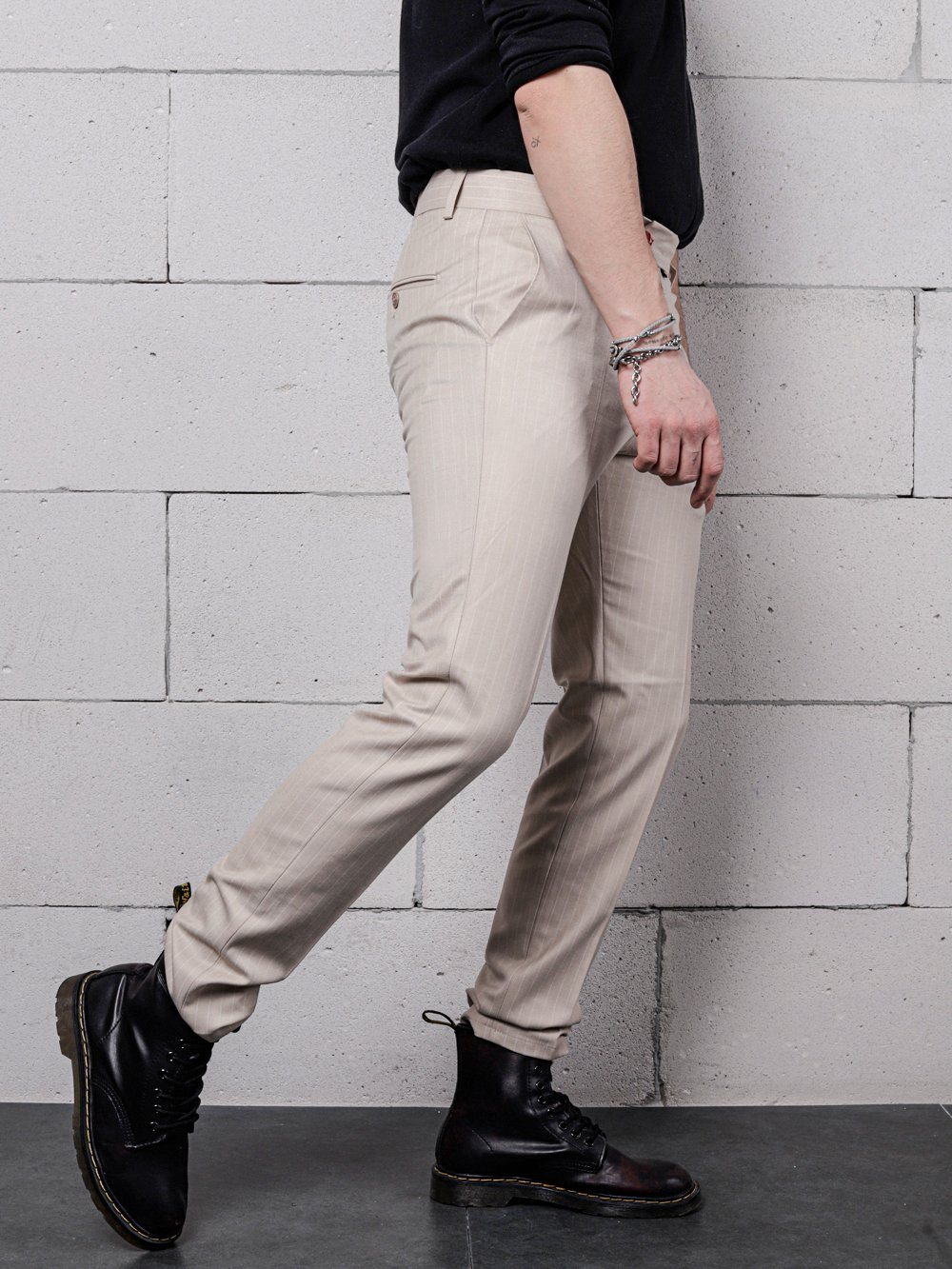 A man wearing a black shirt and beige pants with a trendy LA CREME aesthetic.