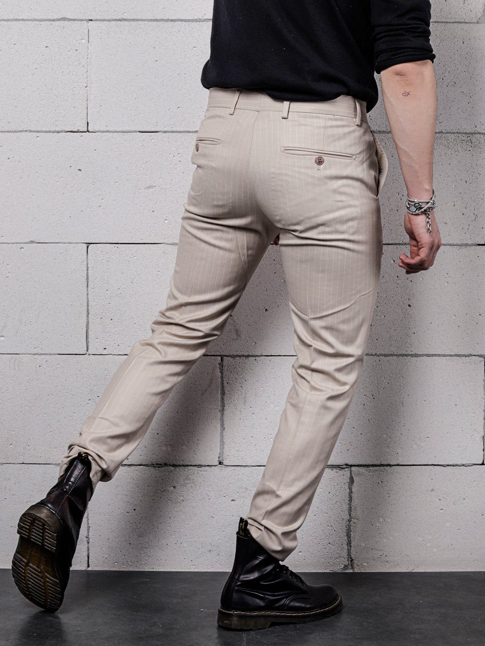 A man is standing with his back to a brick wall, wearing LA CREME skinny fit jeans.