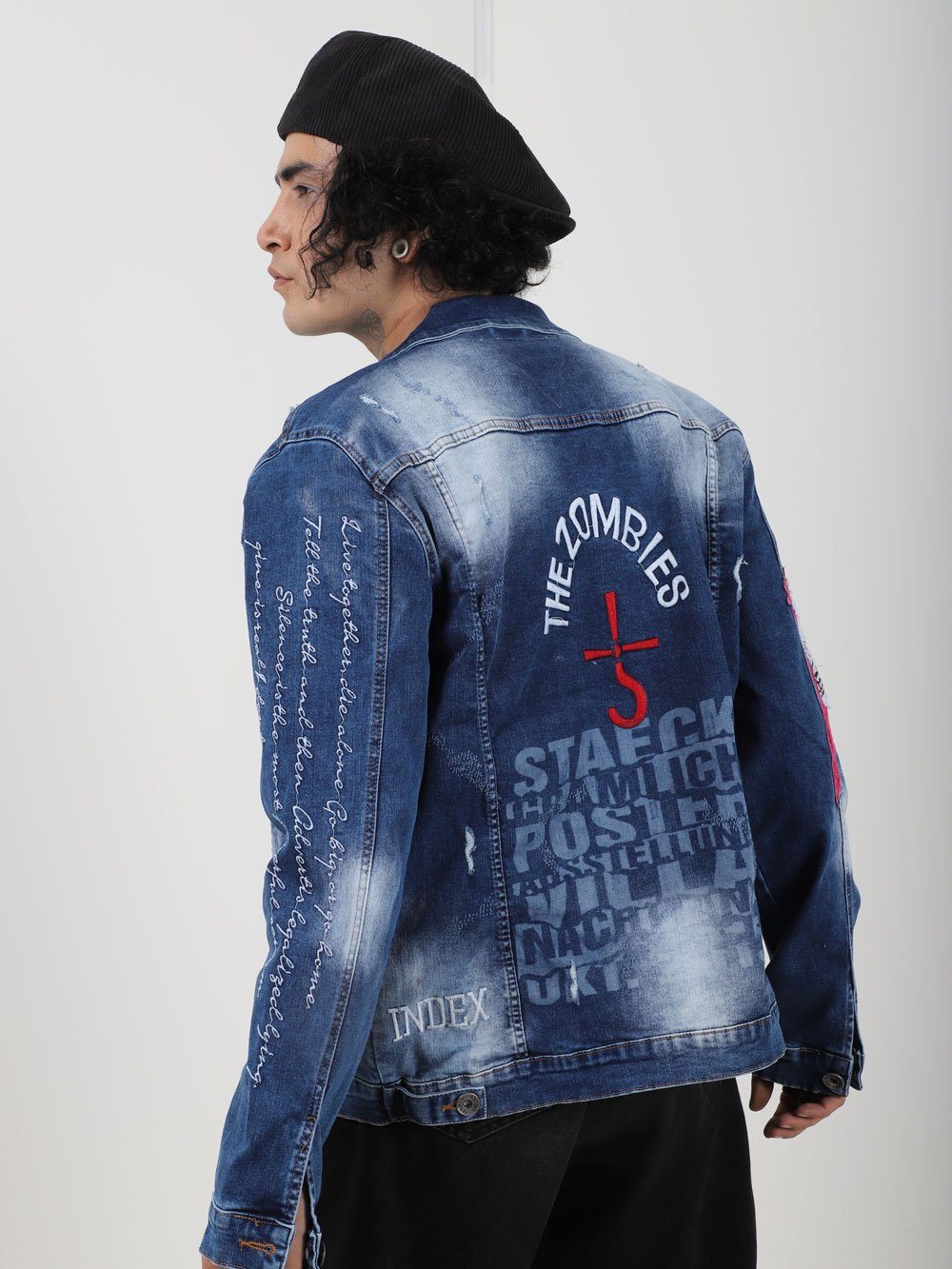 A man wearing THE VETERAN denim jacket with writing on it.