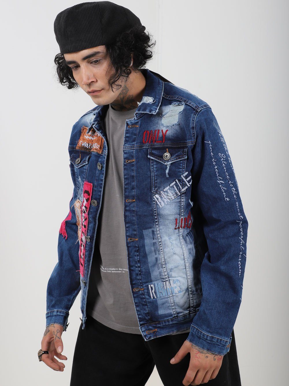 A man wearing THE VETERAN denim jacket with patches on it.