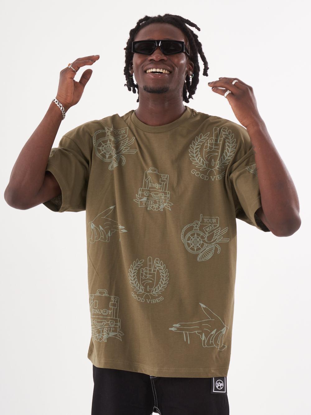A man wearing an olive color oversized VICTORY T-SHIRT by SERNES STREETWEAR with dreadlocks and sunglasses.