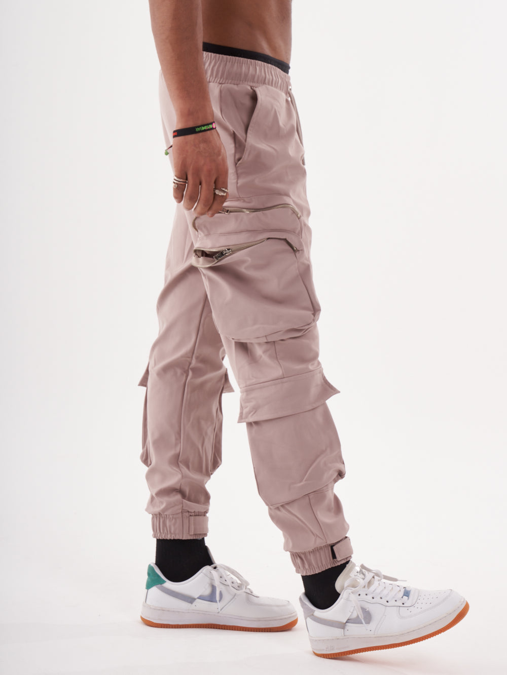A man wearing Spunk Joggers in mauve with cargo pockets and white sneakers.