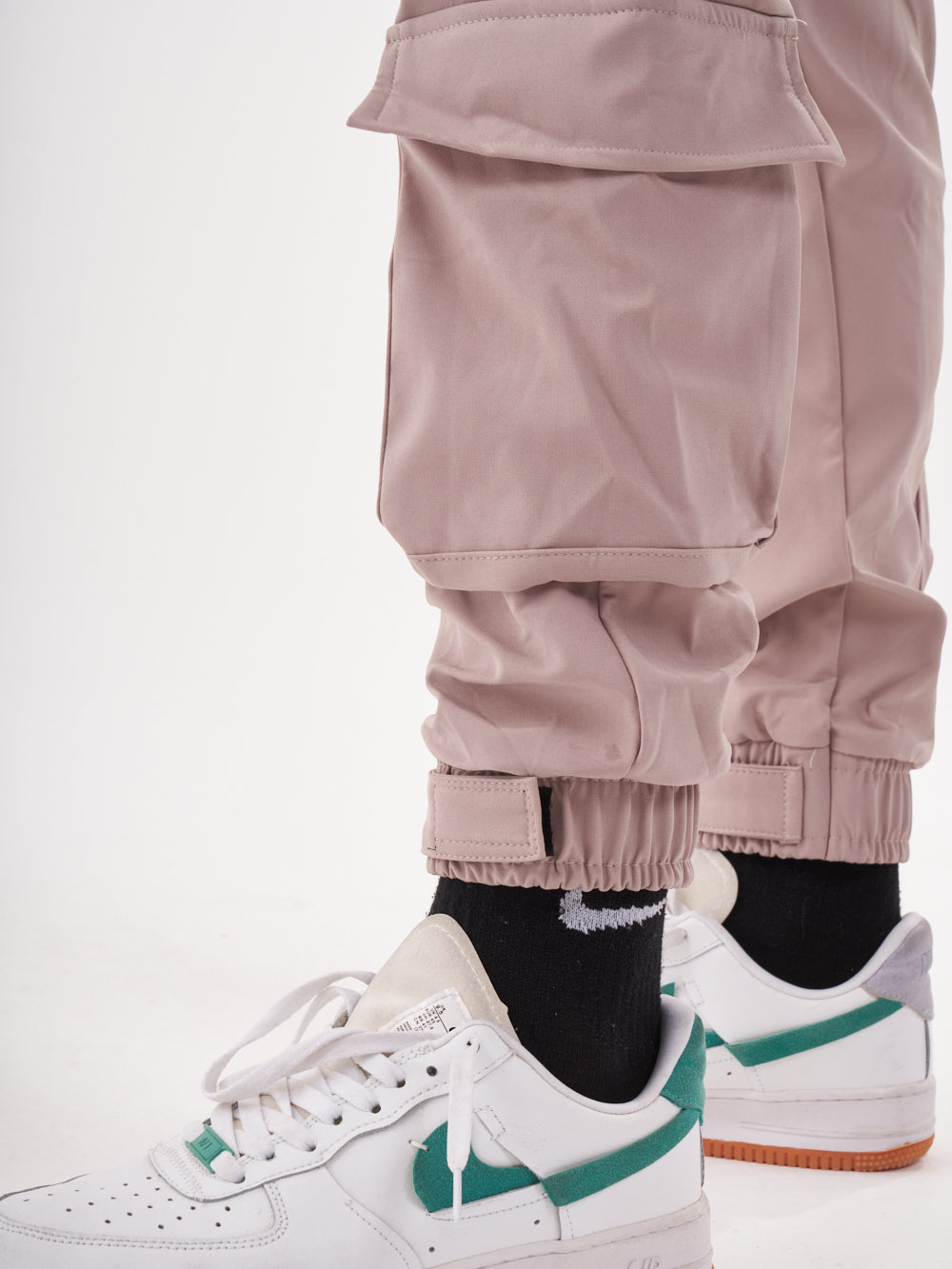 A man wearing a pair of SPUNK JOGGERS | MAUVE cargo pants and white sneakers.