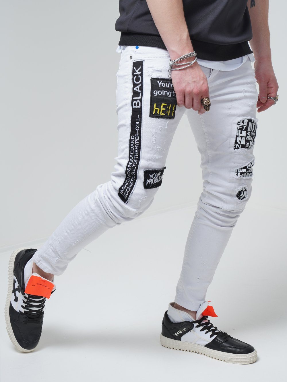 A man wearing WHITE FALCON jeans and black sneakers.