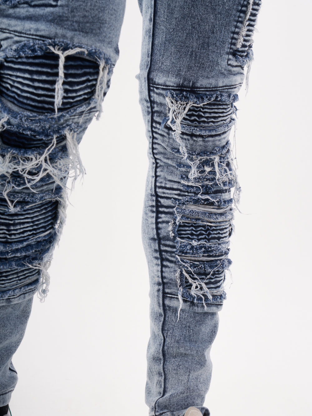 The legs of a man wearing RADICAL jeans.