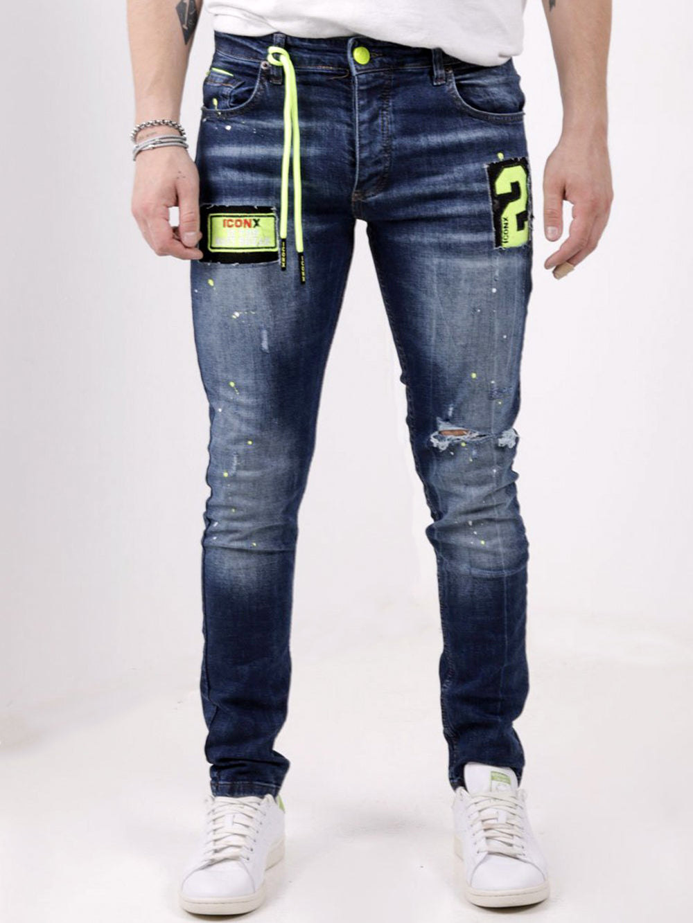 A man wearing a pair of PHOSPHORUS jeans with patches on them.