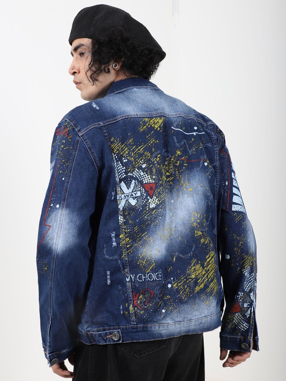 The back of a man wearing an OLD PAINTING denim jacket with graffiti on it.