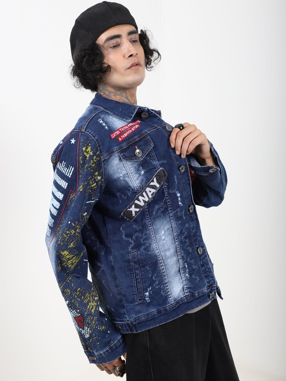 A man wearing an OLD PAINTING denim jacket with paint splatters on it.