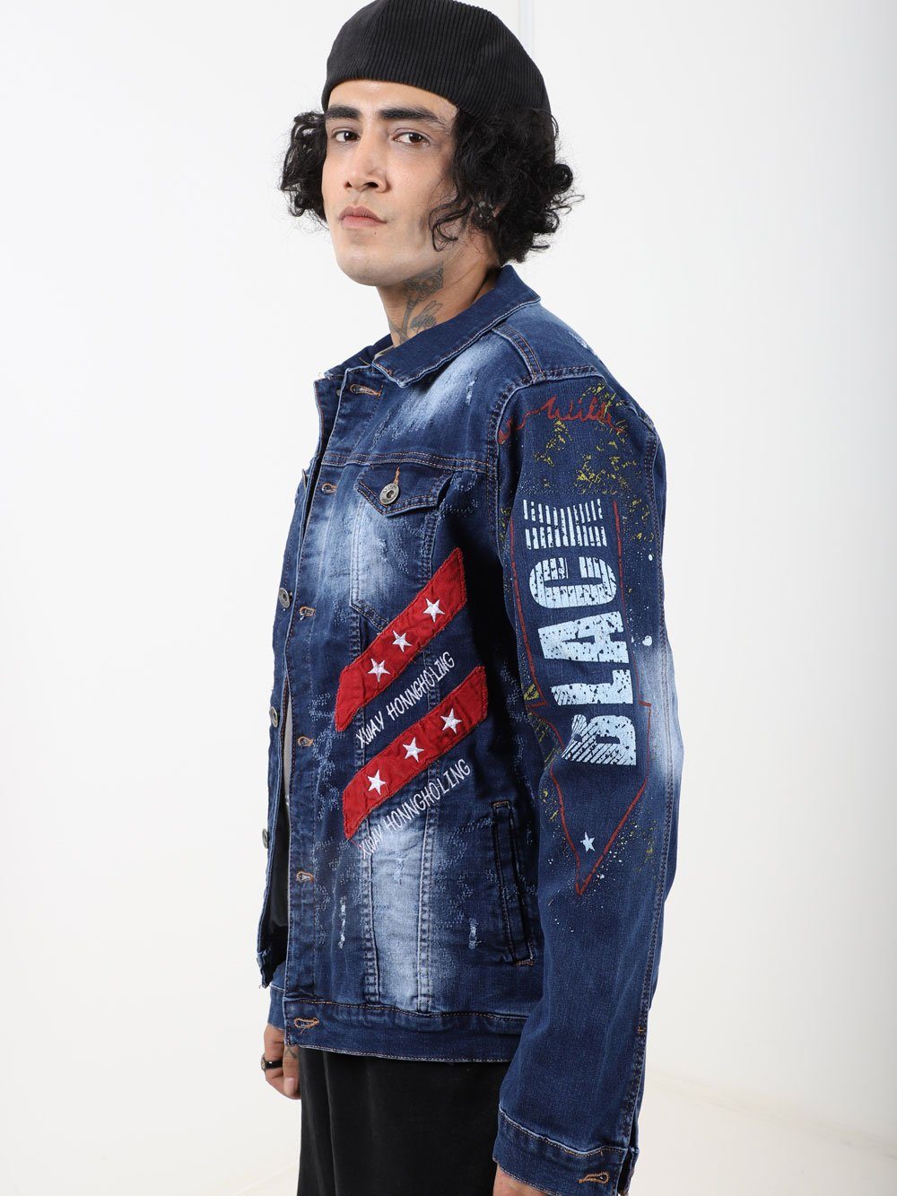 A man wearing an OLD PAINTING denim jacket with stars and stripes on it.