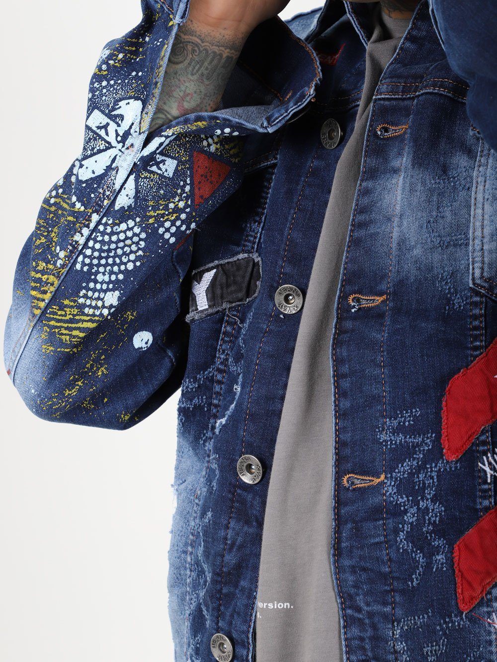 A man wearing an OLD PAINTING denim jacket with embroidered designs.