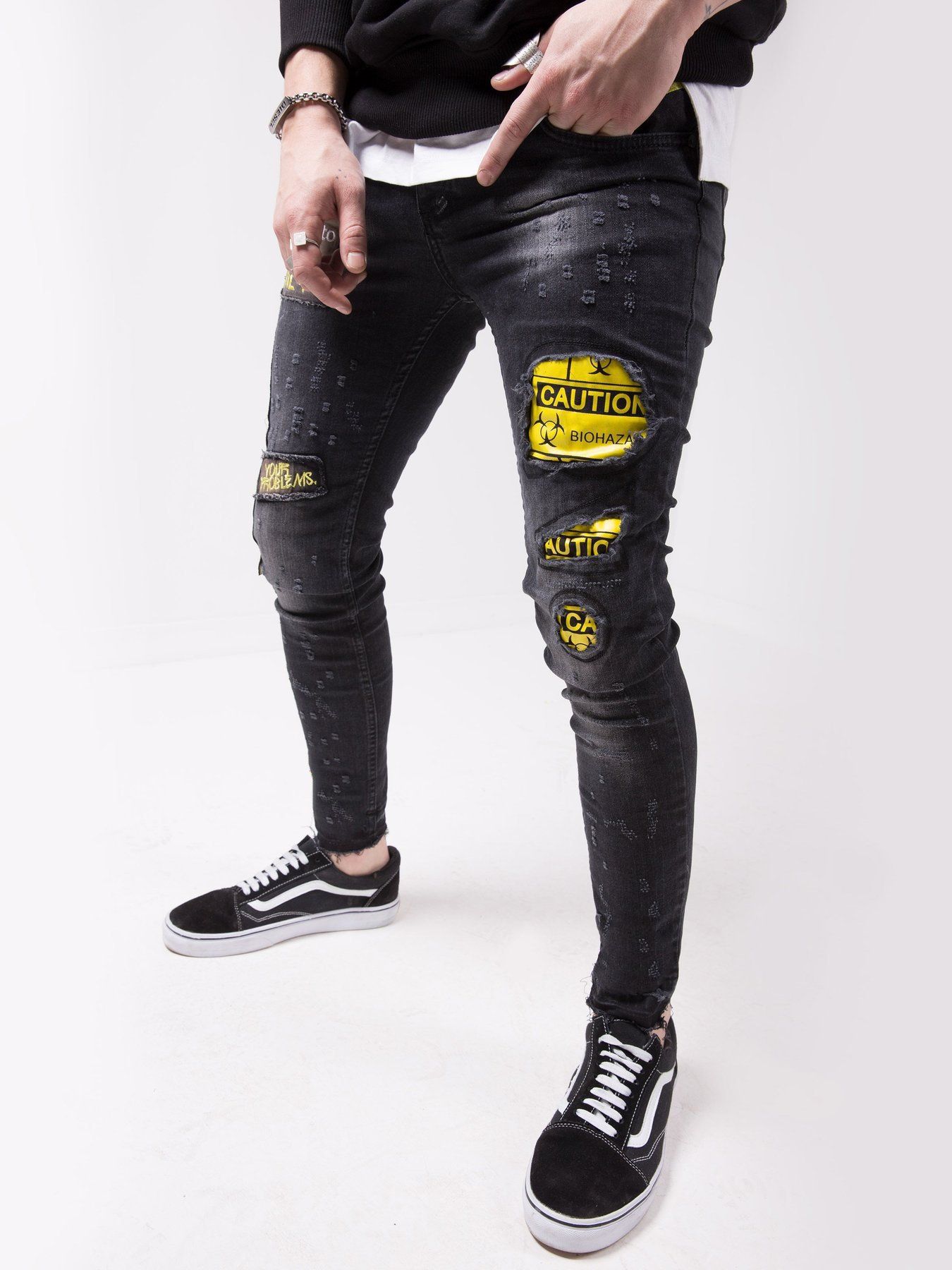 A man wearing BLACK FALCON jeans with yellow patches.
