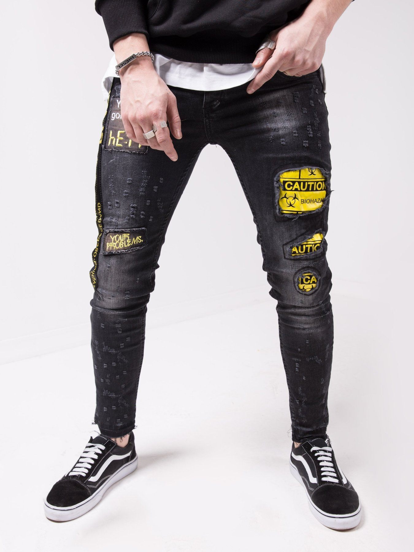 A man wearing a pair of BLACK FALCON jeans with yellow patches.