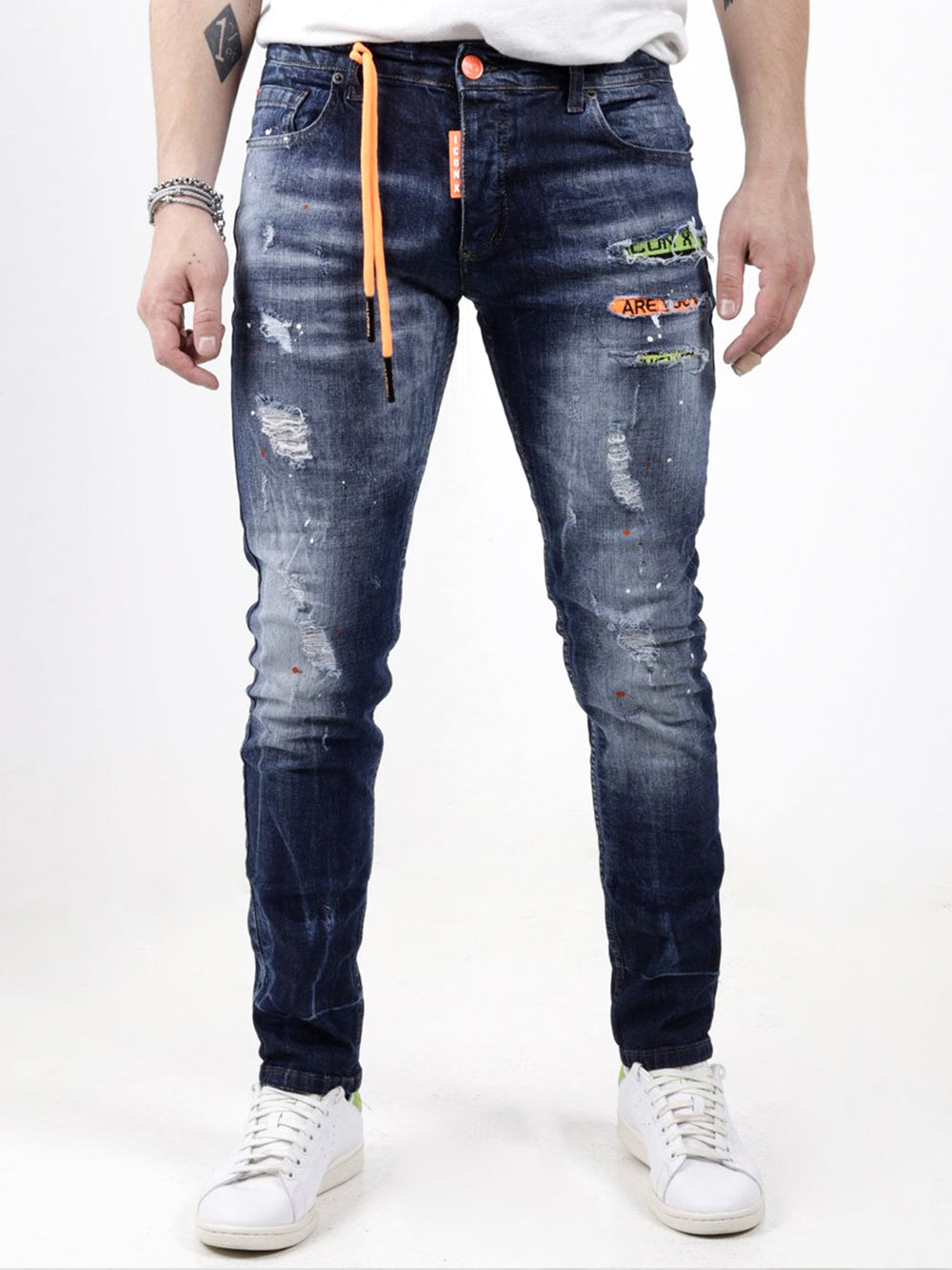 A man wearing ripped jeans with a GRAPHITE zipper.