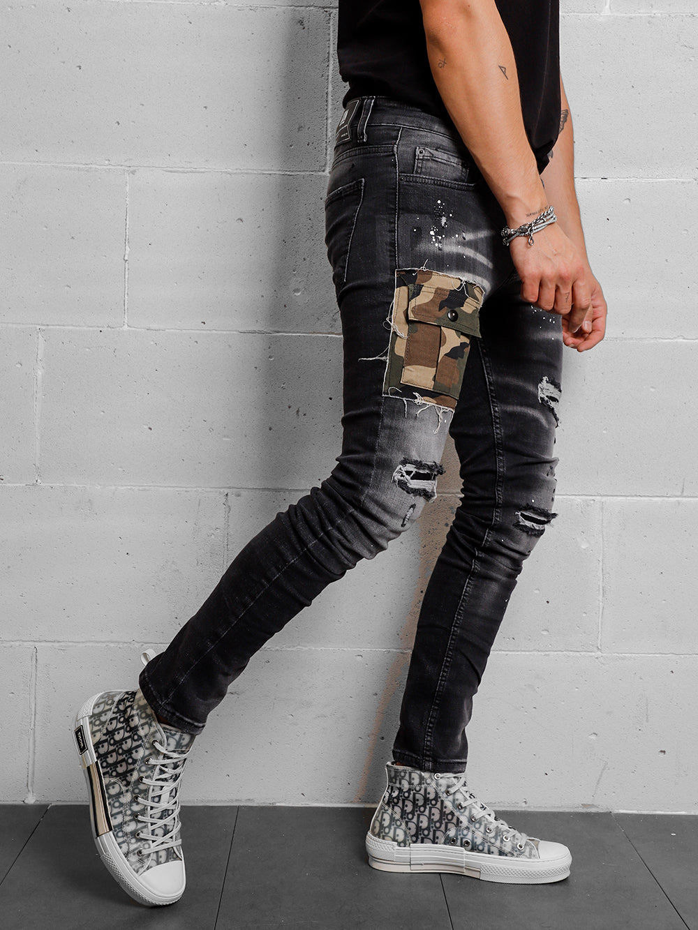 A man wearing CAMOUFLAGE ripped jeans and sneakers.