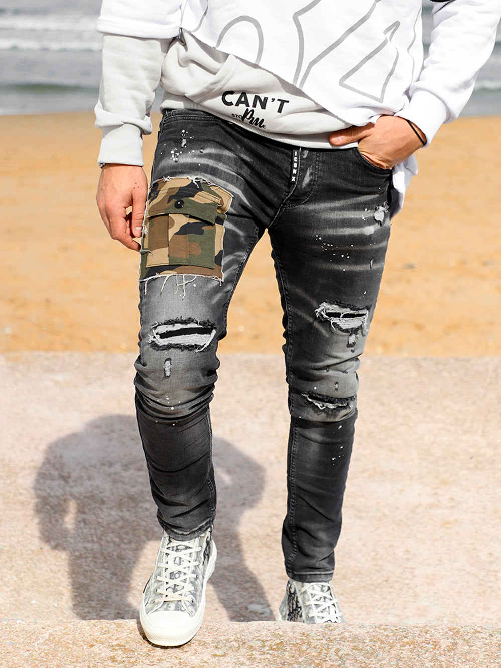 A man wearing ripped jeans and a white t-shirt.