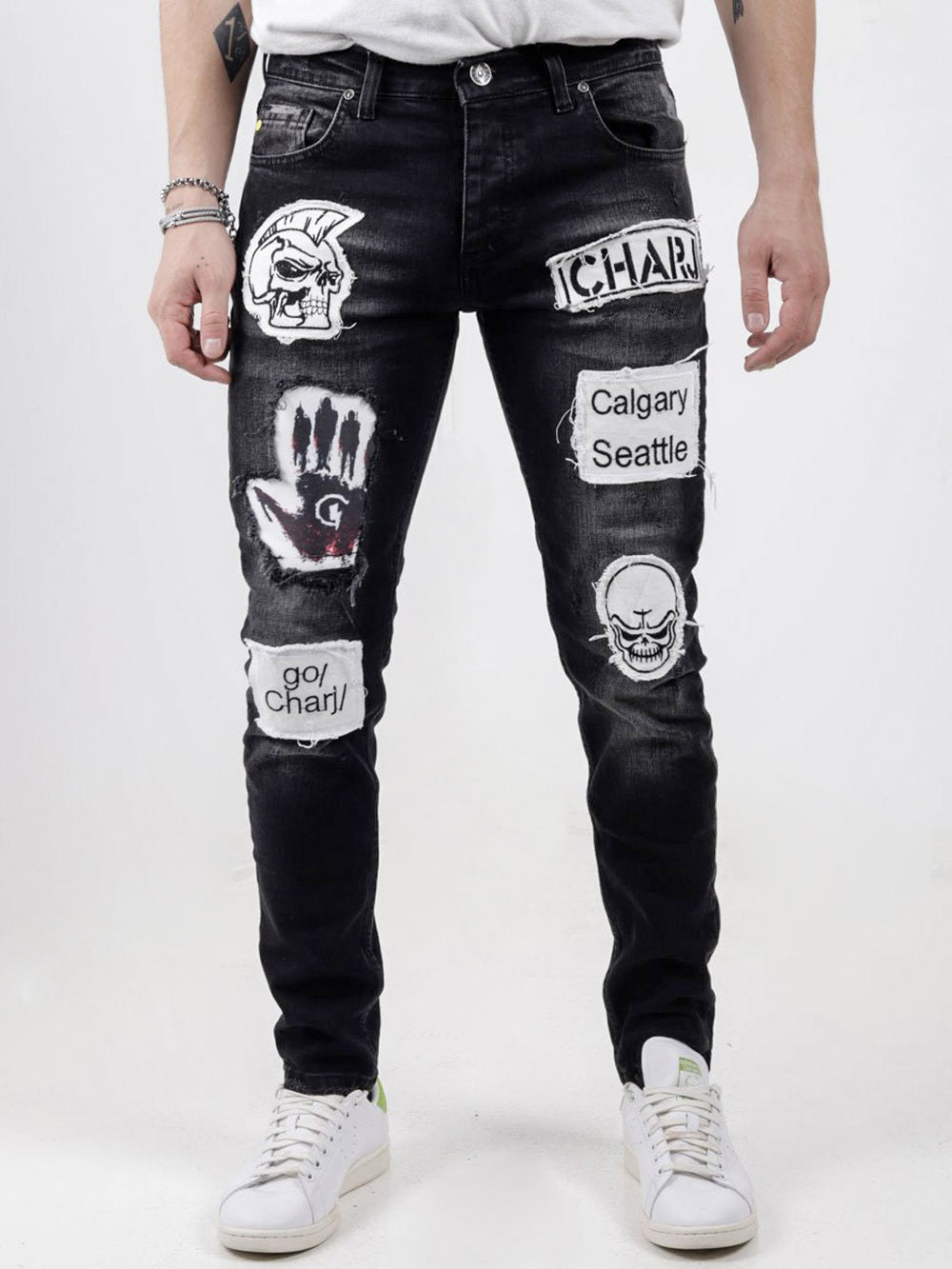 A man wearing a pair of Black Headstone jeans with patches on them.