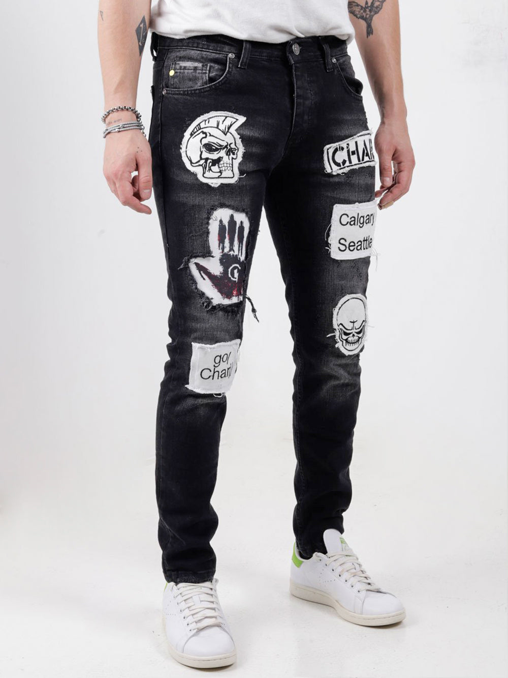 A man wearing black headstone jeans with patches on them.