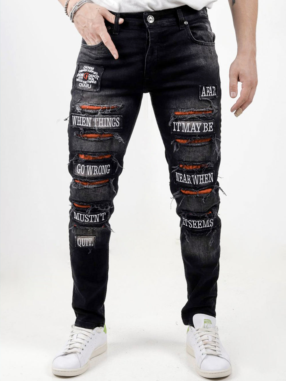 A man wearing a pair of PAW TRAIL jeans with patches on them.