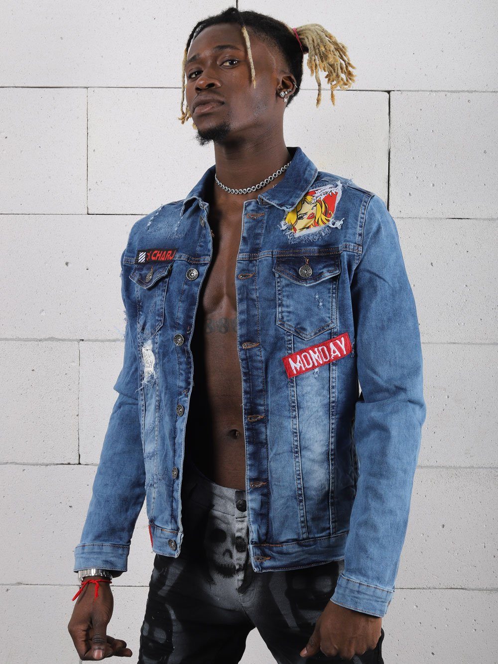 A man wearing a denim jacket with patches in MONDAY streetwear style.