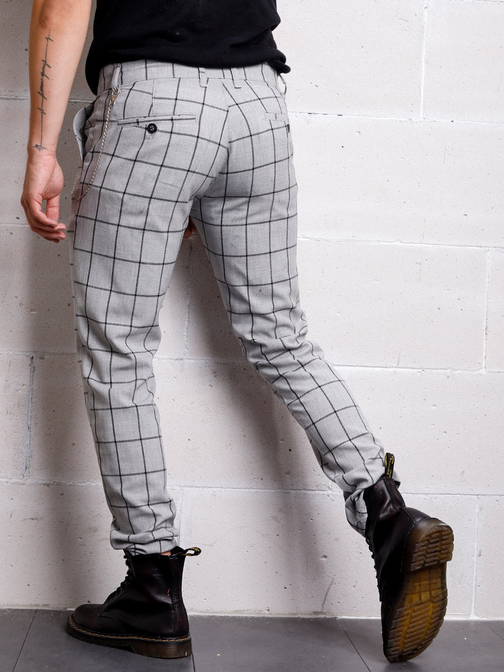 A man is leaning against a wall wearing Graystone pants.