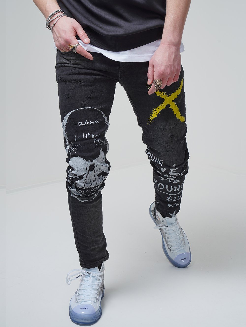 A man wearing a pair of DEAN black jeans with a skull on them.
