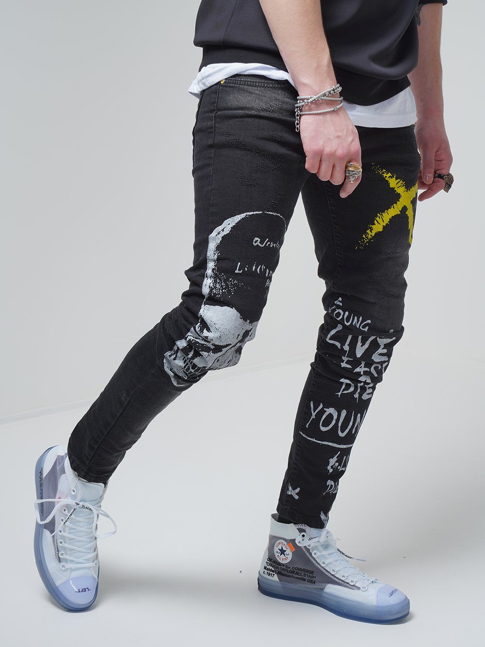 A man wearing a pair of DEAN jeans with graffiti on them.