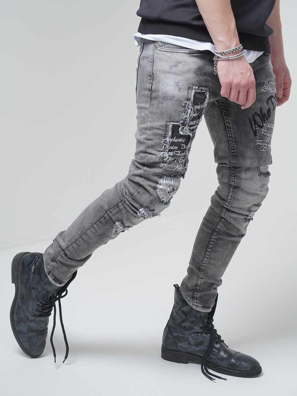A man wearing ripped jeans in a skinny fit and black boots called LONDON.
