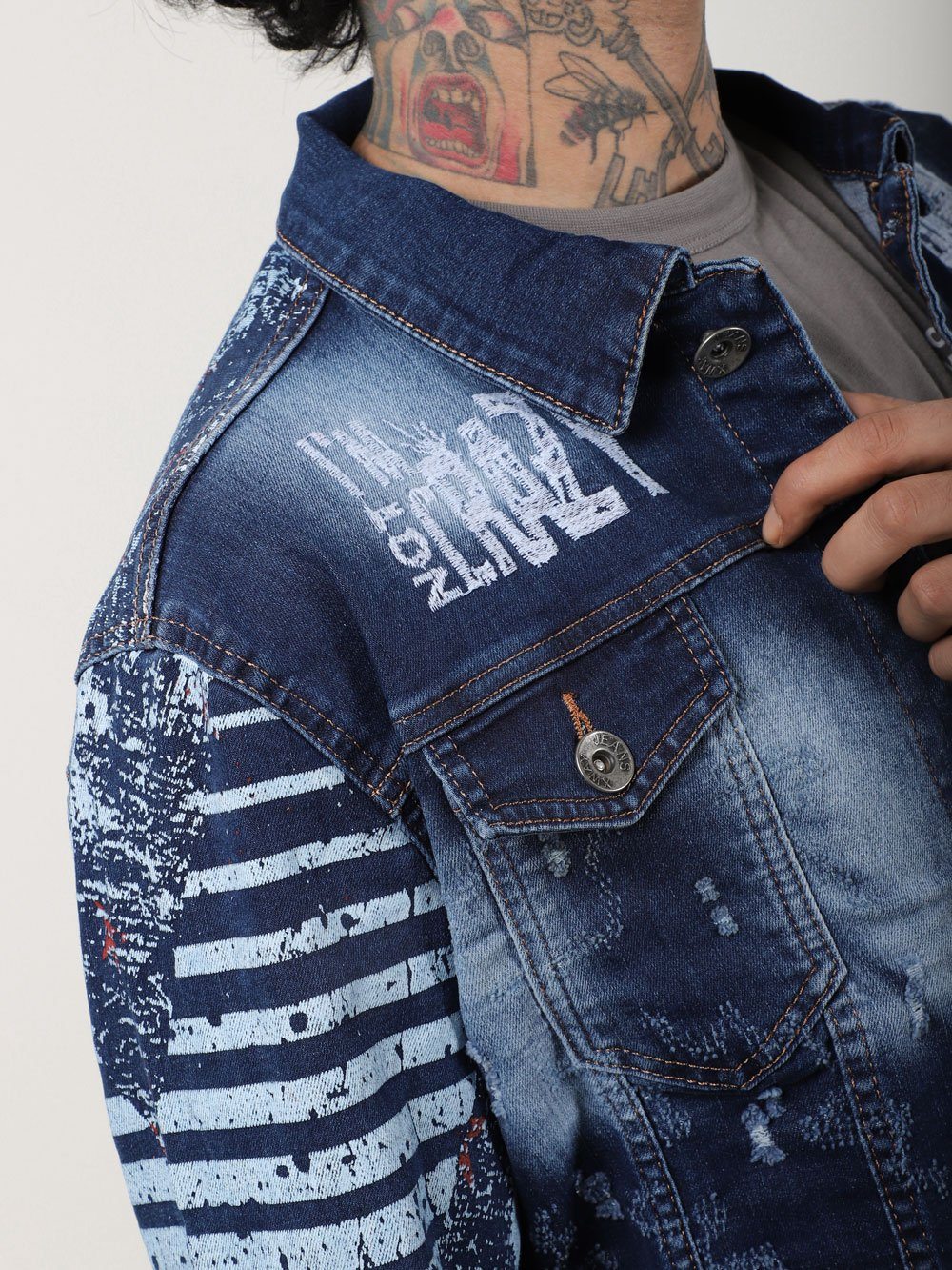 A man wearing a CRAZY CAT denim jacket with tattoos.