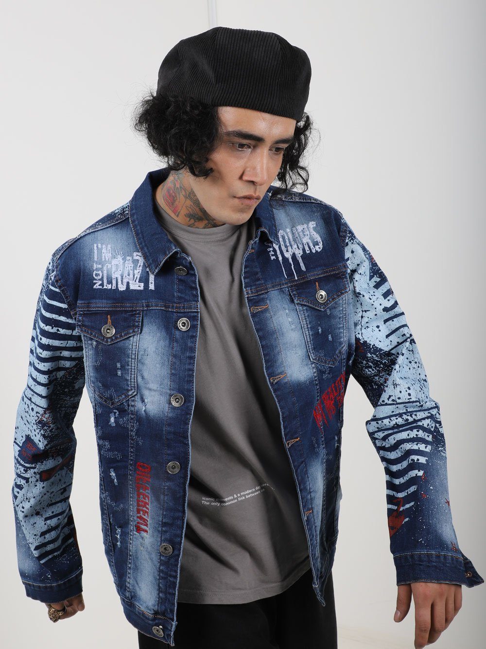 A man wearing a CRAZY CAT denim jacket with graffiti on it.