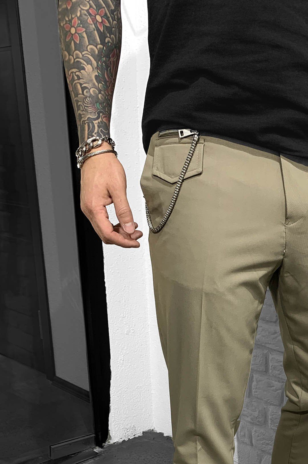 A man wearing GENTLEMAN'S ROLL UP - BEIGE pants with handcrafted details.