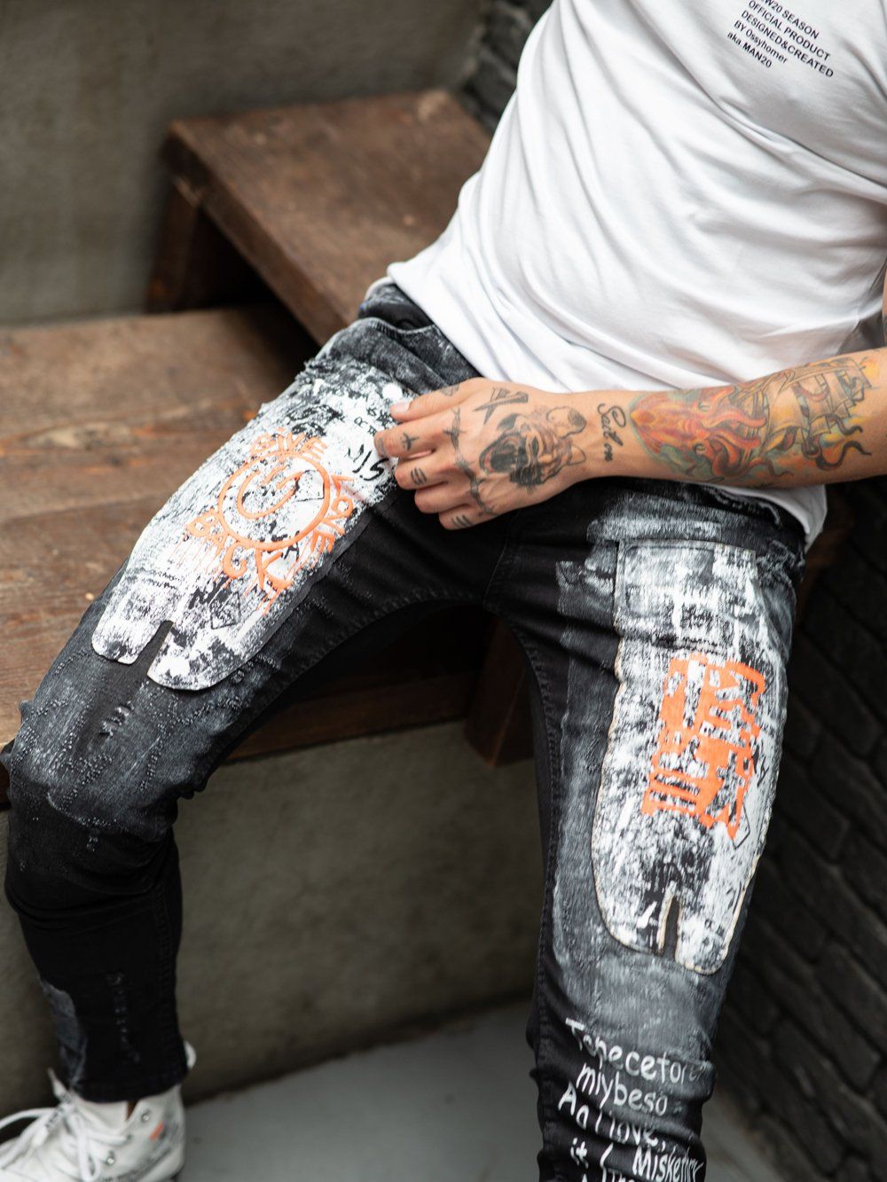 A man sitting on a SIXTY SIX bench with tattoos on his legs.