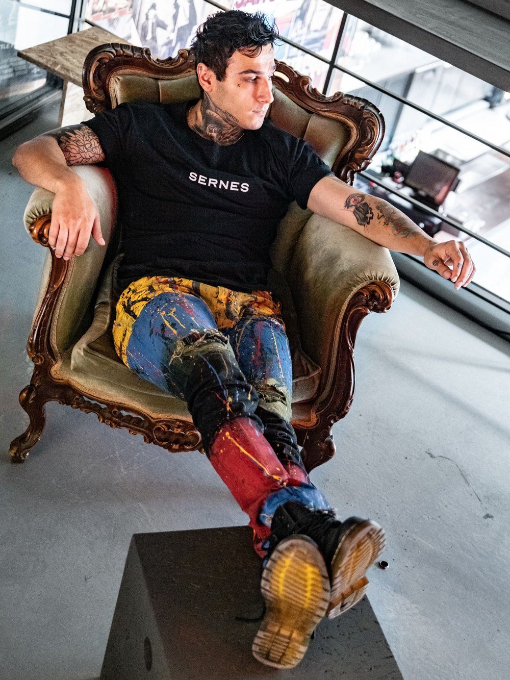 A man sitting in an ornate chair with TOO MUCH tattoos.